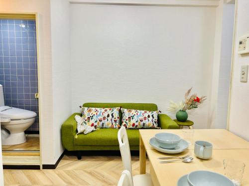 Una sala de estar con un sofá verde y una mesa. en Shinjuku -JX house, en Tokio