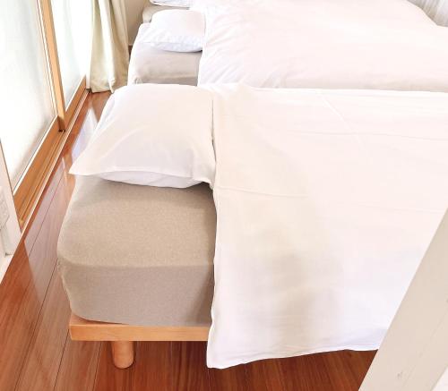 two beds with white sheets on top of a wooden table at かぐら庵 in Kitakata