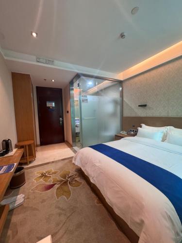 a hotel room with a large bed and a glass door at 海岸秀月楼酒店 in Shenzhen