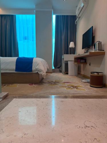 a bedroom with a bed with blue curtains and a television at 海岸秀月楼酒店 in Shenzhen