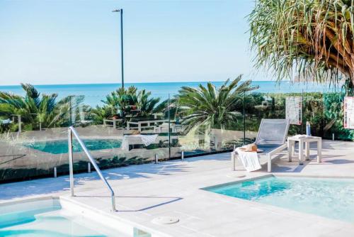a villa with a pool and a chair and the ocean at Seahaven Noosa Beachfront Resort in Noosa Heads