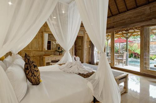 a bedroom with a bed with white drapes at Astala Ubud Villa in Ubud
