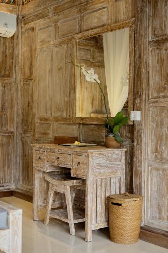 a wooden dressing table with a mirror and a stool at Astala Ubud Villa in Ubud