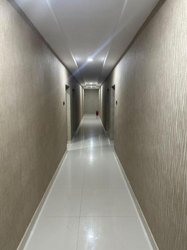 a long hallway with white tile floors and walls at Jaya Tourist Home in Varkala