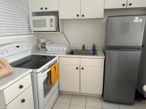 a kitchen with white cabinets and a stainless steel refrigerator at Sunset Cove - Vacation In Paradise! in Nassau
