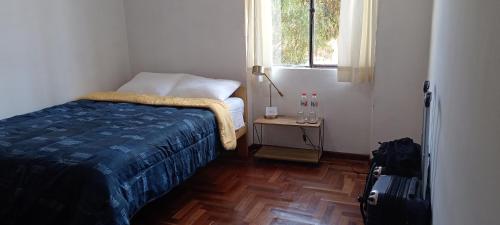 a small bedroom with a bed and a window at Sonqo Andino Departamento in Cusco