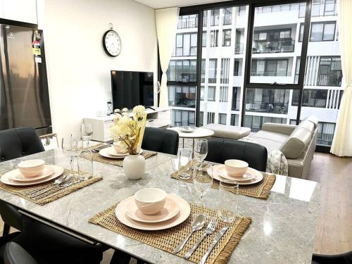 a dining room with a table with plates and glasses at Modern Chic Apartment Close to Sydney Airport in Sydney