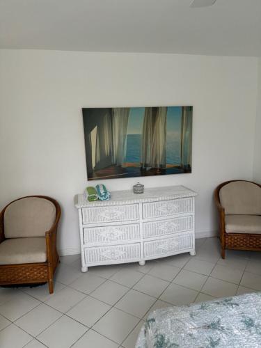 a living room with two chairs and a white dresser at Sunset Cove - Vacation In Paradise! in Nassau