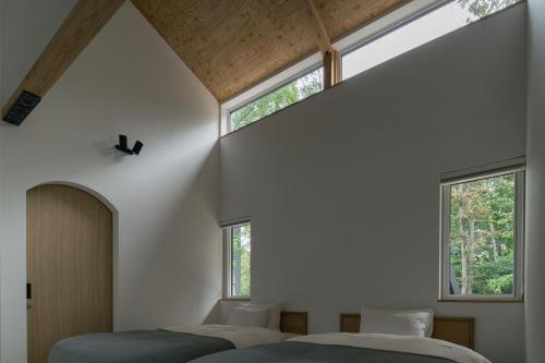 two beds in a bedroom with two windows at 山郷 Villas in Nature in Otaru