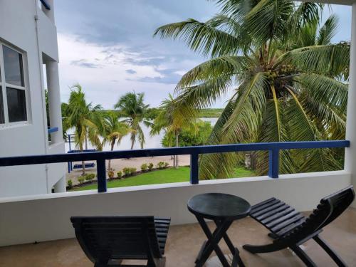 a balcony with two chairs and a table and palm trees at Brahma Blue Resort in San Pedro