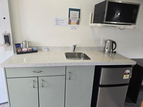 a kitchen counter with a sink and a microwave at Kerikeri Homestead Motel & Apartments in Kerikeri