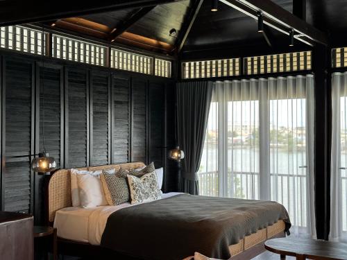 a bedroom with a bed with black walls and windows at rongmai mahachai cafe and stay in Samut Sakhon