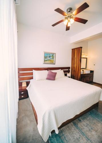 a bedroom with a white bed with a ceiling fan at Brahma Blue Resort in San Pedro