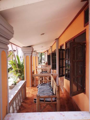 a porch with benches and tables on a house at Khamphouy Guesthouse in Champasak