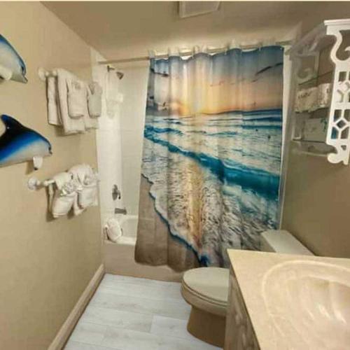 a bathroom with a shower curtain with a ocean at Tortuga Inn Beach Resort Unit #229 in Bradenton Beach
