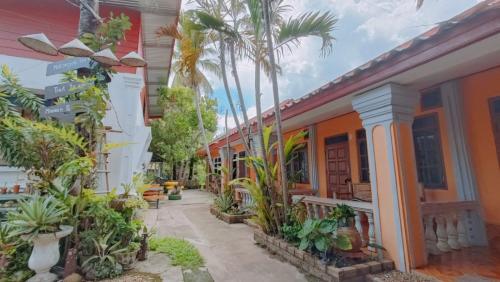 a courtyard of a house with palm trees and plants at Khamphouy Guesthouse in Champasak