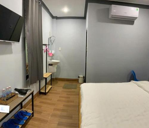 a bedroom with a bed and a television and a bathroom at Nomad Stay in Phan Rang