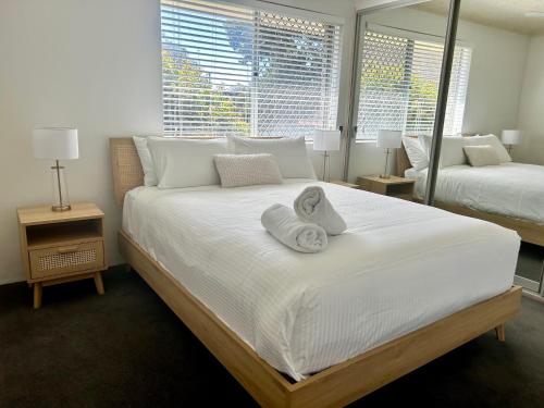 a bedroom with a large white bed with towels on it at Camelot Unit 12 in Forster