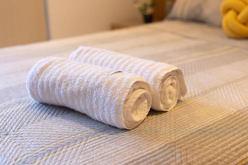 two rolls of white towels on a bed at Studio com Varanda a 100 metros da praia in Tambaú
