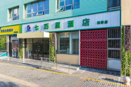 a building with a red door on a street at Qiqiaowu Hotel Beijing Daxing Airport Line Caoqiao Subway Station Branch in Beijing