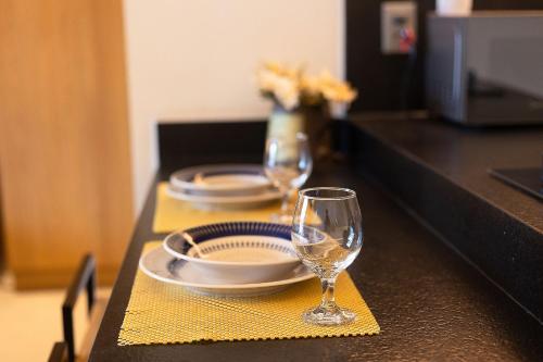 a table with two plates and wine glasses on it at Studio com Varanda a 100 metros da praia in Tambaú