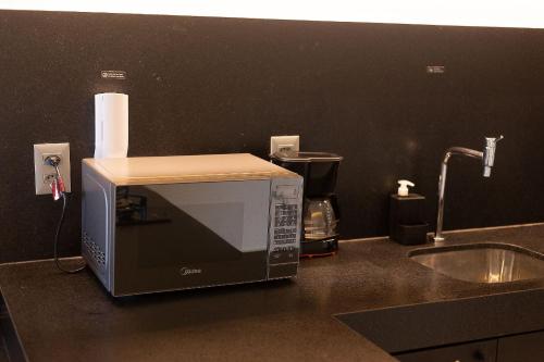 a microwave sitting on a kitchen counter next to a sink at Studio com Varanda a 100 metros da praia in Tambaú
