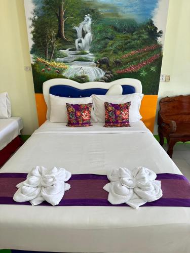 ein Schlafzimmer mit einem großen weißen Bett mit einem Gemälde in der Unterkunft ลูกจ่าปองโฮม Lukjapong Home in Ranong