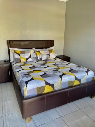 a large bed in a bedroom with a colorful comforter at SapzRes at Klerksdorp in Klerksdorp