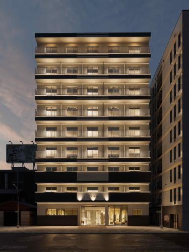 a tall building with lights on at b&天下茶屋店 in Osaka