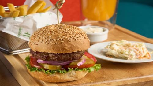 a hamburger on a wooden tray with a plate of fries at Holiday Inn Tashkent City by IHG in Tashkent