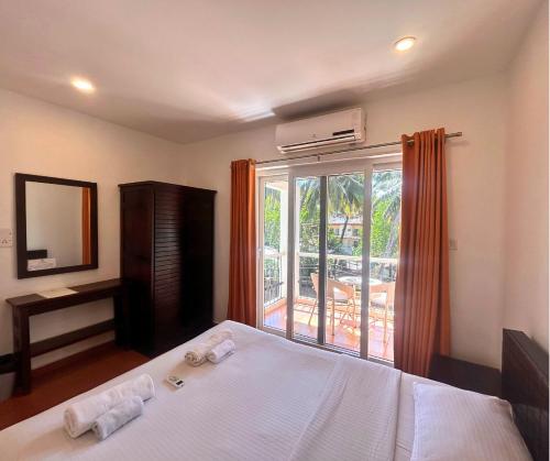 a bedroom with a bed and a large window at Jungle Hut-Annabelle's Beach Apartments at Bernard Simao,Calangute,Goa in Candolim
