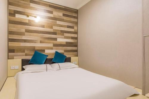 a bedroom with a large white bed with blue pillows at Qiqiaowu Hotel Beijing Daxing Airport Line Caoqiao Subway Station Branch in Beijing
