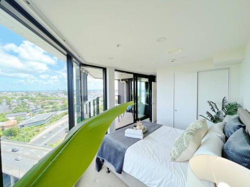 a bedroom with a green couch and a large window at Amazing Sunset View Penthouse in Auckland
