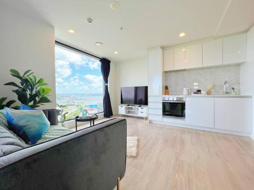 a living room with a couch and a large window at Amazing Sunset View Penthouse in Auckland
