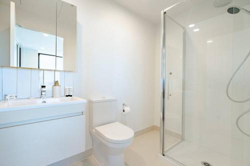 a white bathroom with a toilet and a shower at Amazing Sunset View Penthouse in Auckland