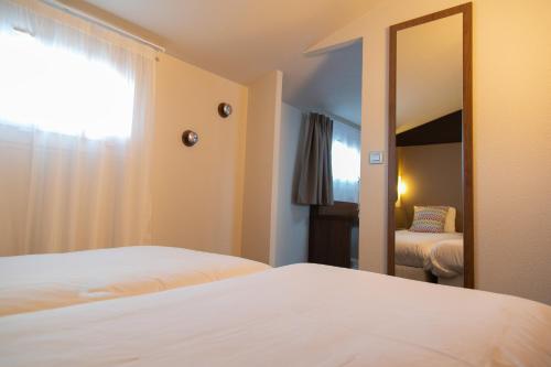 a hotel room with two beds and a mirror at Campanile Toulouse - Blagnac Aéroport in Blagnac