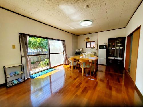a living room with a table and a large window at 一棟貸し みじょら しーばなコテージ in Akagina