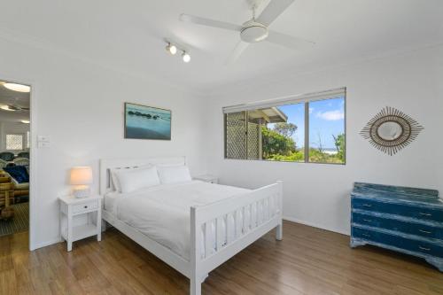 Un dormitorio blanco con una cama blanca y una ventana. en Classic Beach House on Surfside - Pet Friendly, en Pottsville