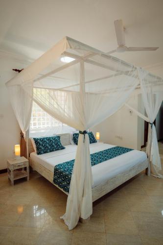 a bedroom with a bed with a canopy at Villa Jasmine - Ocean Front in Bwejuu