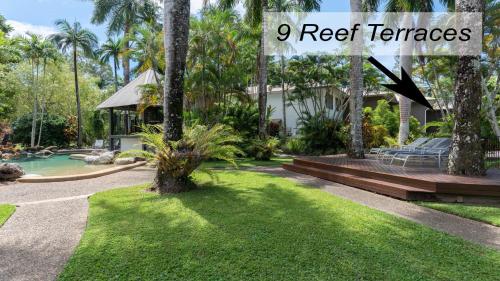 a yard with a pool and a house with palm trees at 9 Reef Terraces Port Douglas in Port Douglas