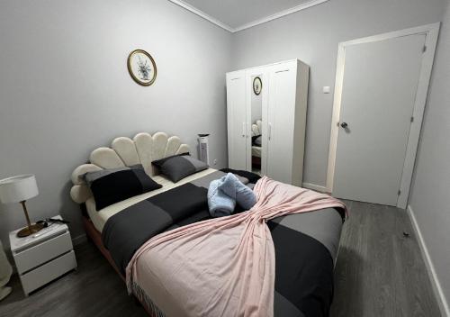 a bedroom with a large bed and a clock on the wall at Chachino Guesthouse -5 Mins walk to Train & Bus Station in Agualva