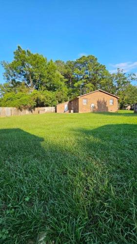 a field of green grass with a house in the background at Cozy 2BR sleeps 6 near ECU Stadium and Hospital in Greenville