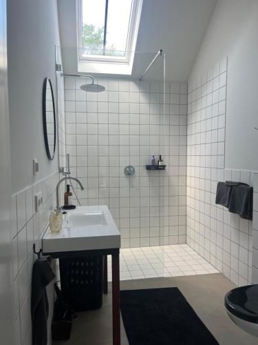 a white bathroom with a sink and a shower at Gastenverblijf 'tsiishokje' in Lioessens