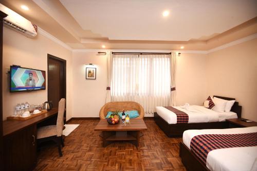 a hotel room with two beds and a desk and a table at Skye Inn Kathmandu in Kathmandu