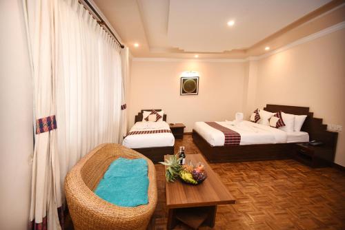 a hotel room with two beds and a chair at Skye Inn Kathmandu in Kathmandu