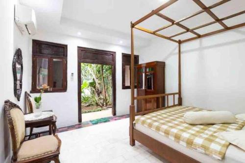 une chambre avec un lit à baldaquin et une chaise dans l'établissement Vintage Room 1 in Joglo House By penggemarlawas, à Kamparganya