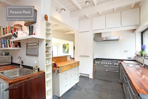 a kitchen with white cabinets and a sink at A rural retreat with space and light in Birlingham