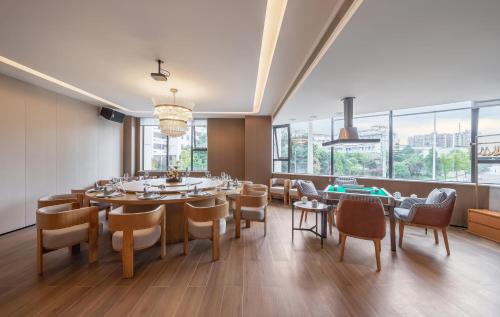 a dining room with a table and chairs and windows at Wellstay Hotel in Jianyang