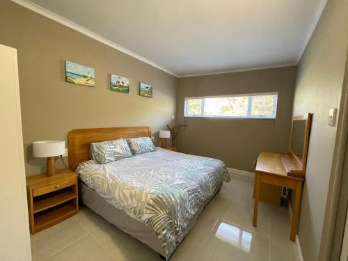 a bedroom with a bed and a table and a window at Bushmansriver Tree-House in Bushmans River Village