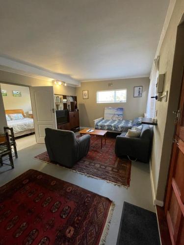 a living room with a bed and a couch and chairs at Bushmansriver Tree-House in Bushmans River Village